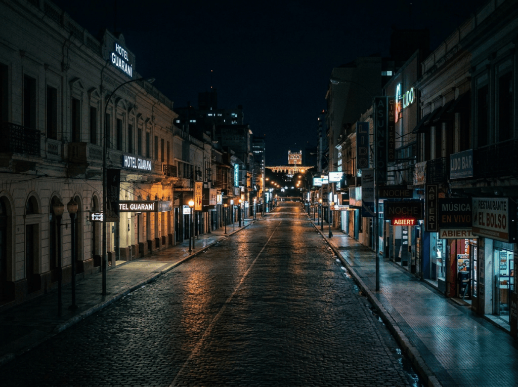 Busy nighttime street with Hotel Guaraní, neon signs, taxis, and pedestrians